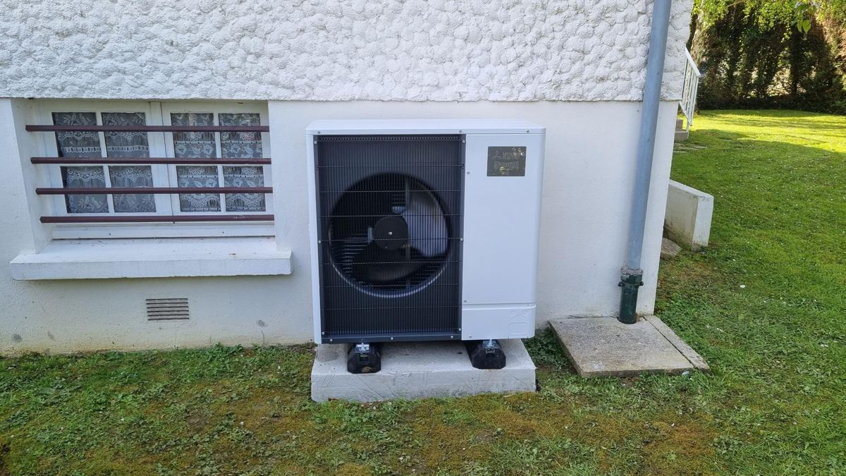 Unité extérieure Mitsubishi Electric posée sur socle contre une maison