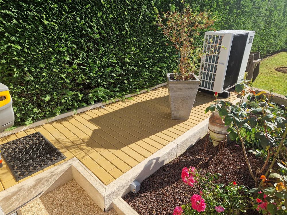 Unité extérieure posée sur plots dans un jardin